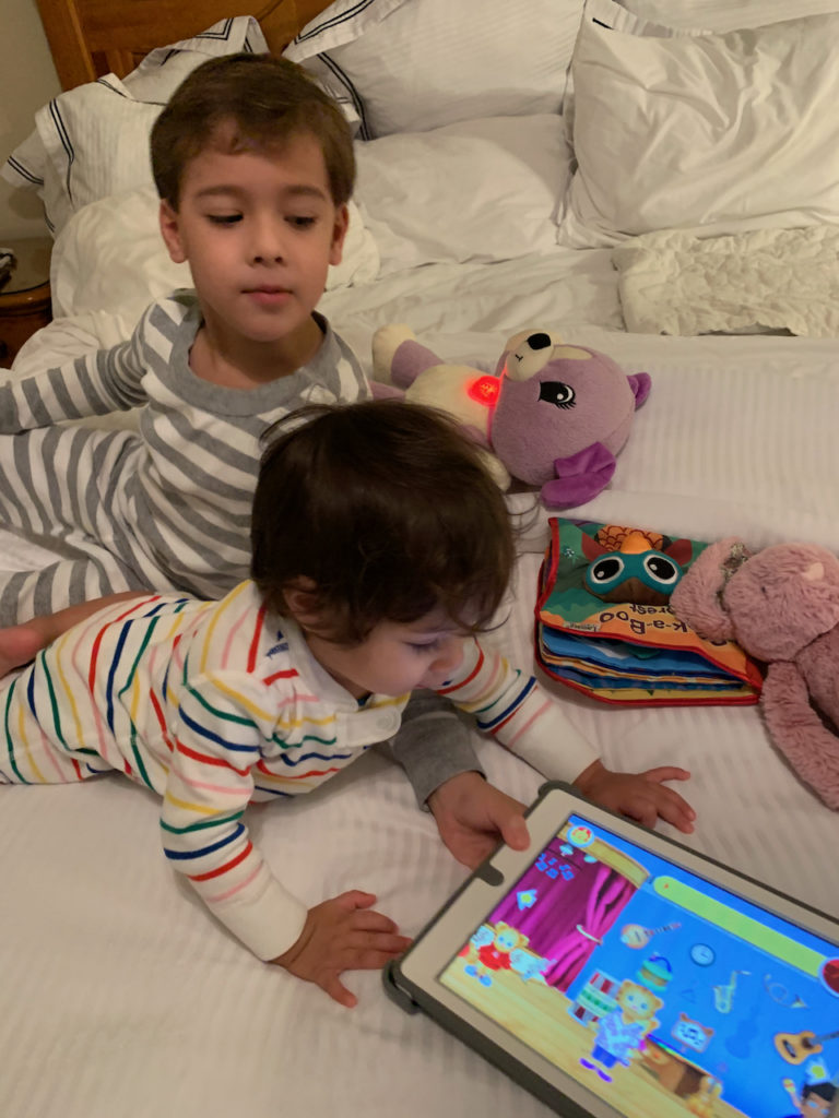 kids on a hotel bed with an iPad